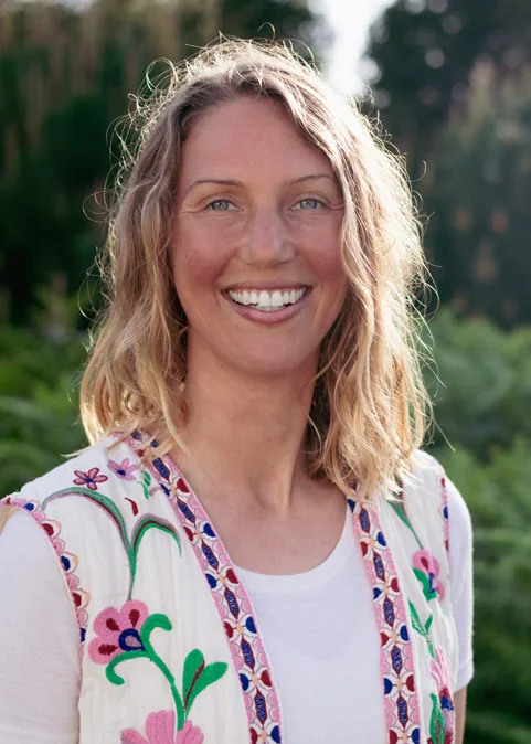 Katharina Mülke lächelt in die Kamera, hinter ihr Grün im Abendlicht.